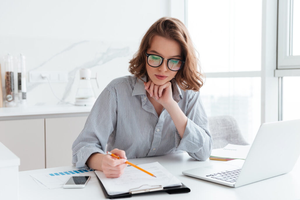 Home 12 young concentrated businesswoman glasses striped shirt working with papers home